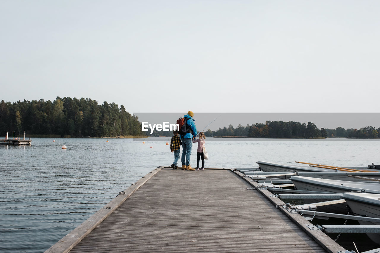 Father and his children happily fishing on the end of a pier together