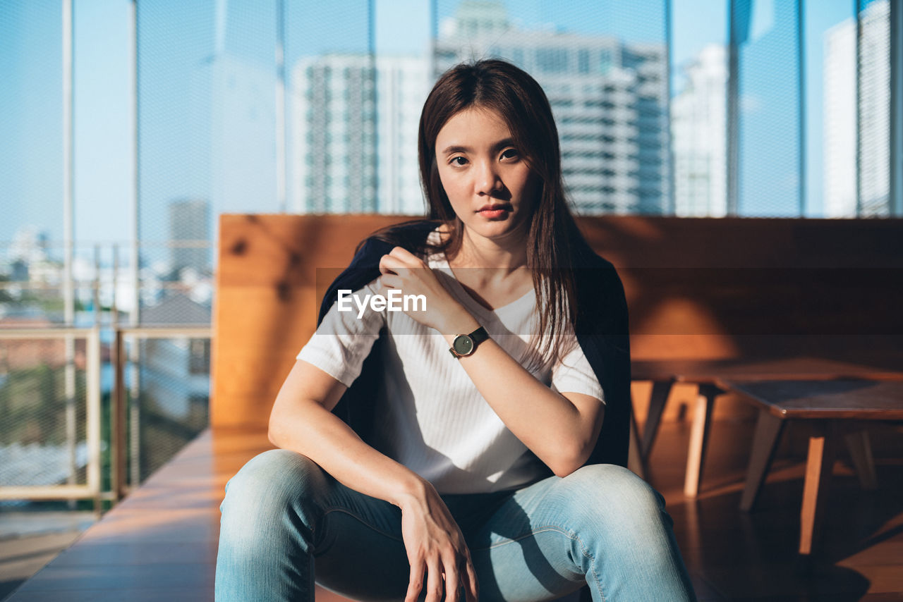 Portrait of beautiful young woman sitting on chair in restaurant