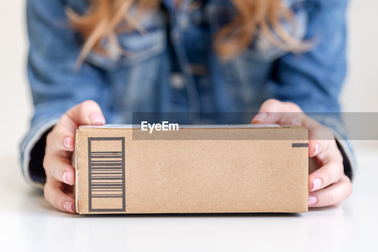 Woman holding in hands delivered goods in cardboard box. mock-up friendly design with copy space.