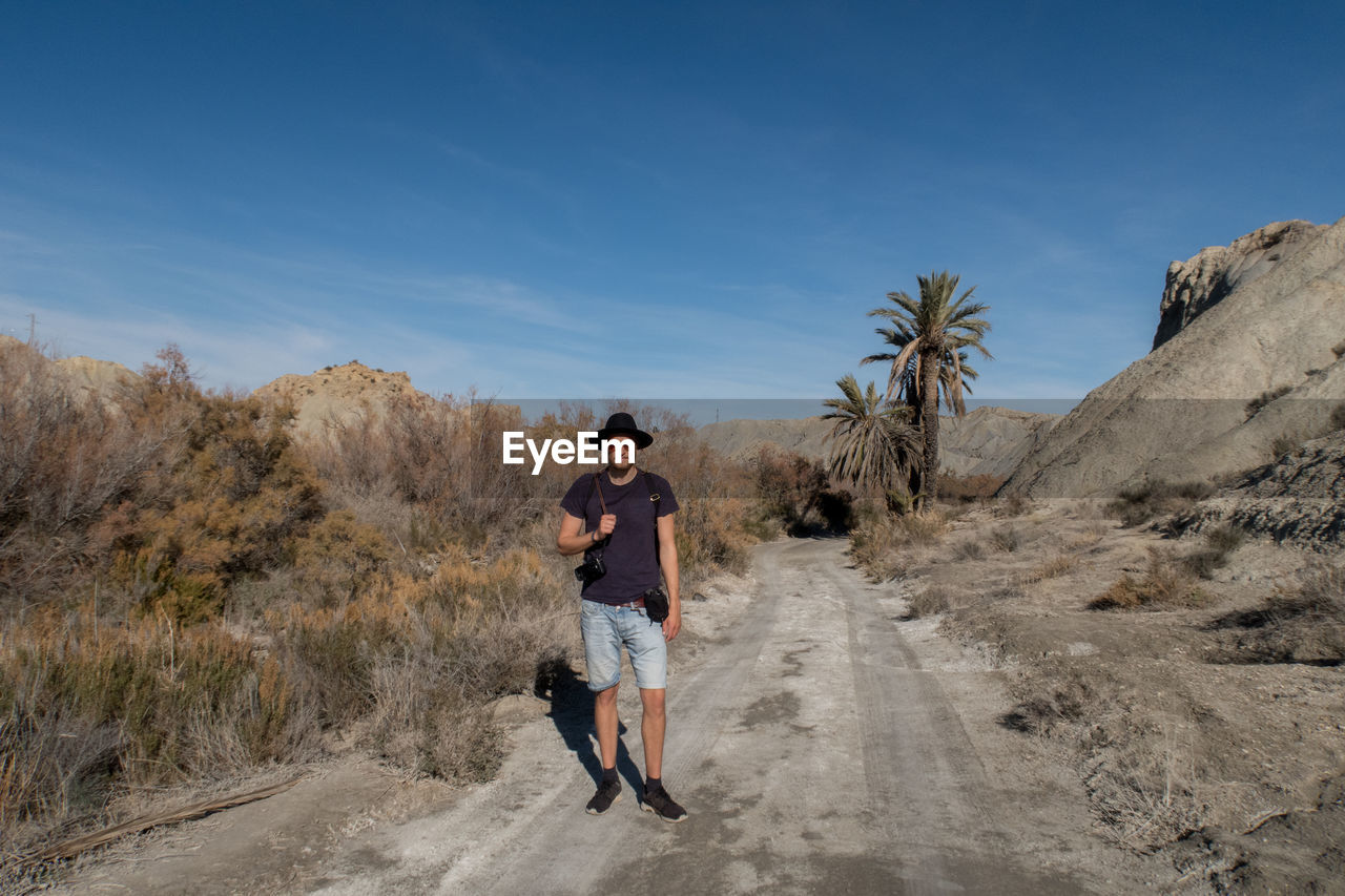 Full length portrait of man standing on road against sky