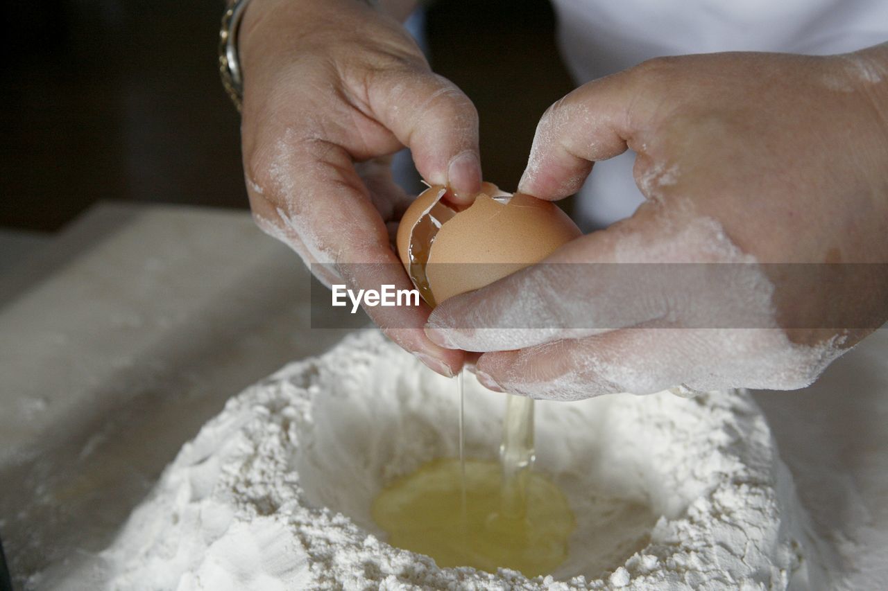 Close-up of woman hands that prepares dough for italian pasta with egg and flour