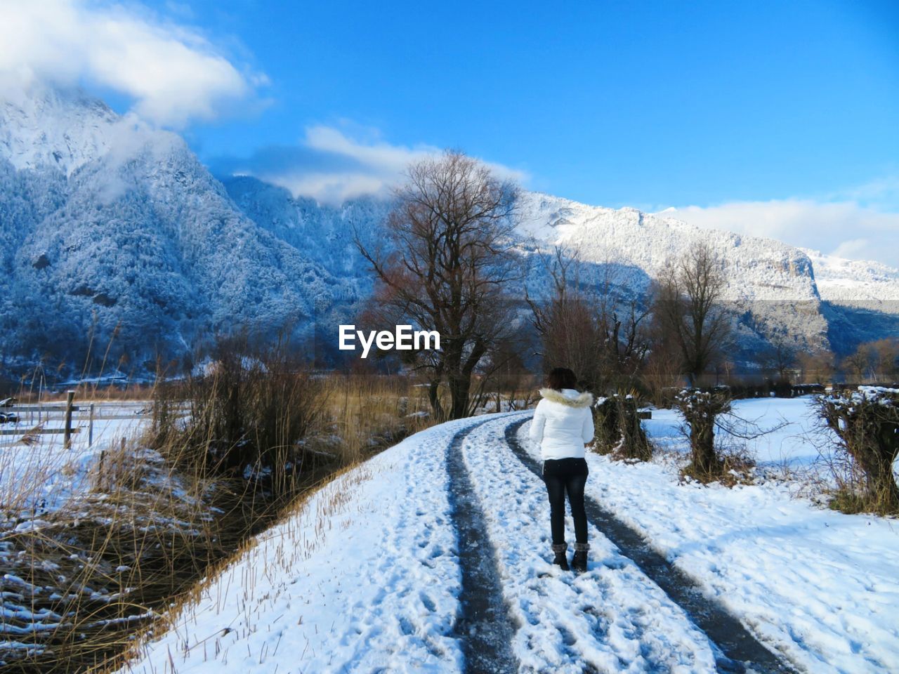 REAR VIEW OF PERSON WALKING ON SNOW COVERED MOUNTAIN