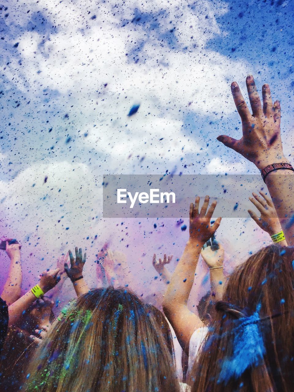 Close-up of people playing with powder paint against sky