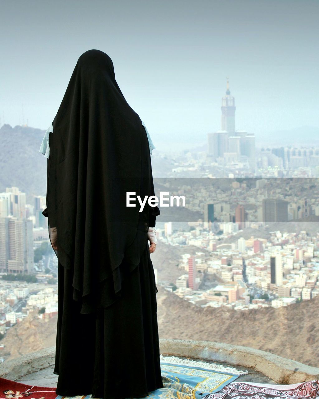 Rear view of woman standing on carpet against city