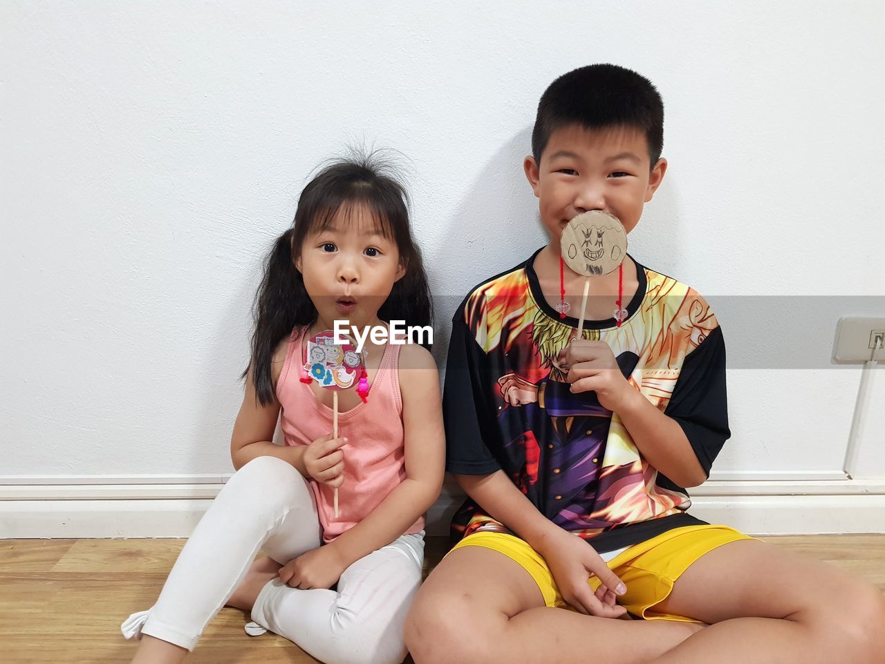 Portrait of cute siblings with props sitting on floor at home
