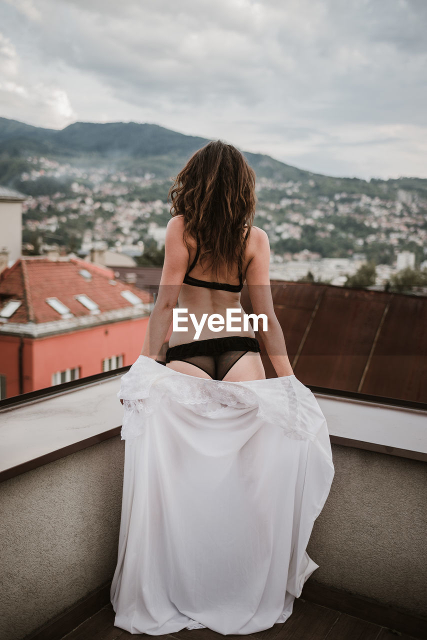 Rear view of woman in bikini while standing on building terrace