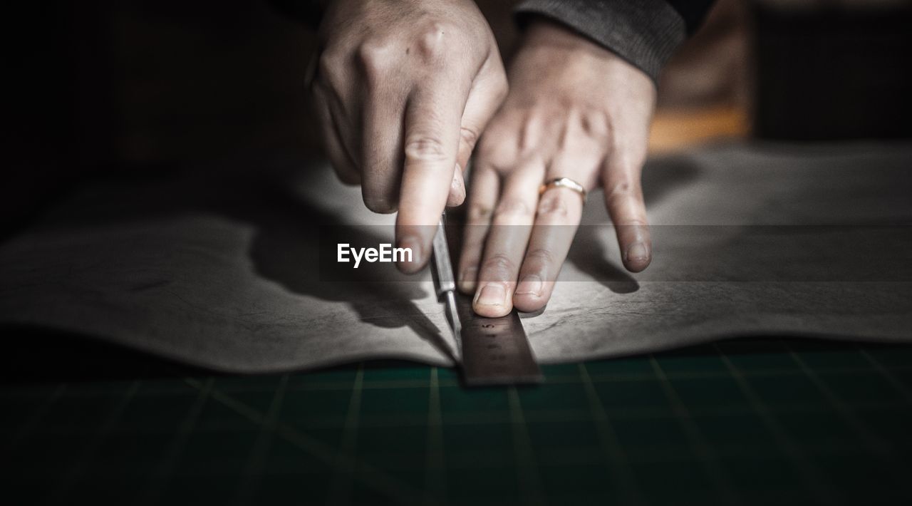 Cropped image of hands marking on paper with ruler