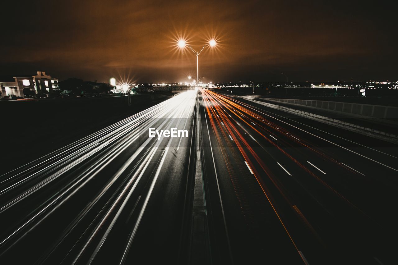 LIGHT TRAILS ON ROAD AGAINST SKY AT NIGHT