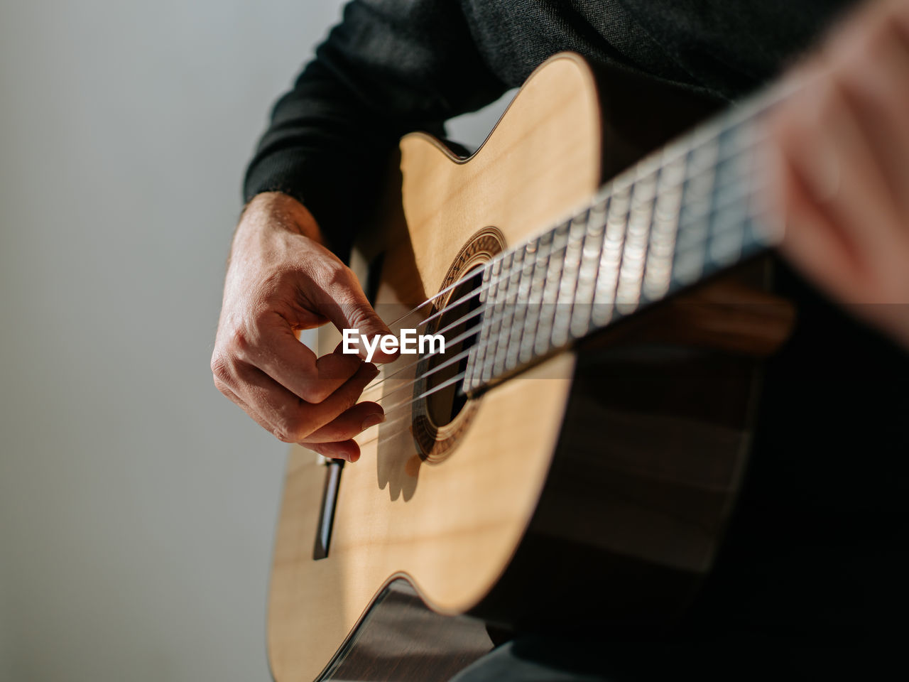 Midsection of man playing classical guitar