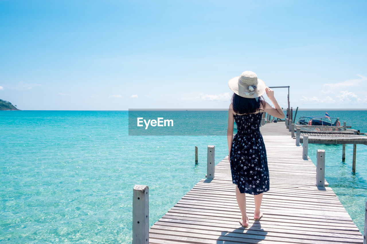 REAR VIEW OF WOMAN LOOKING AT SEA