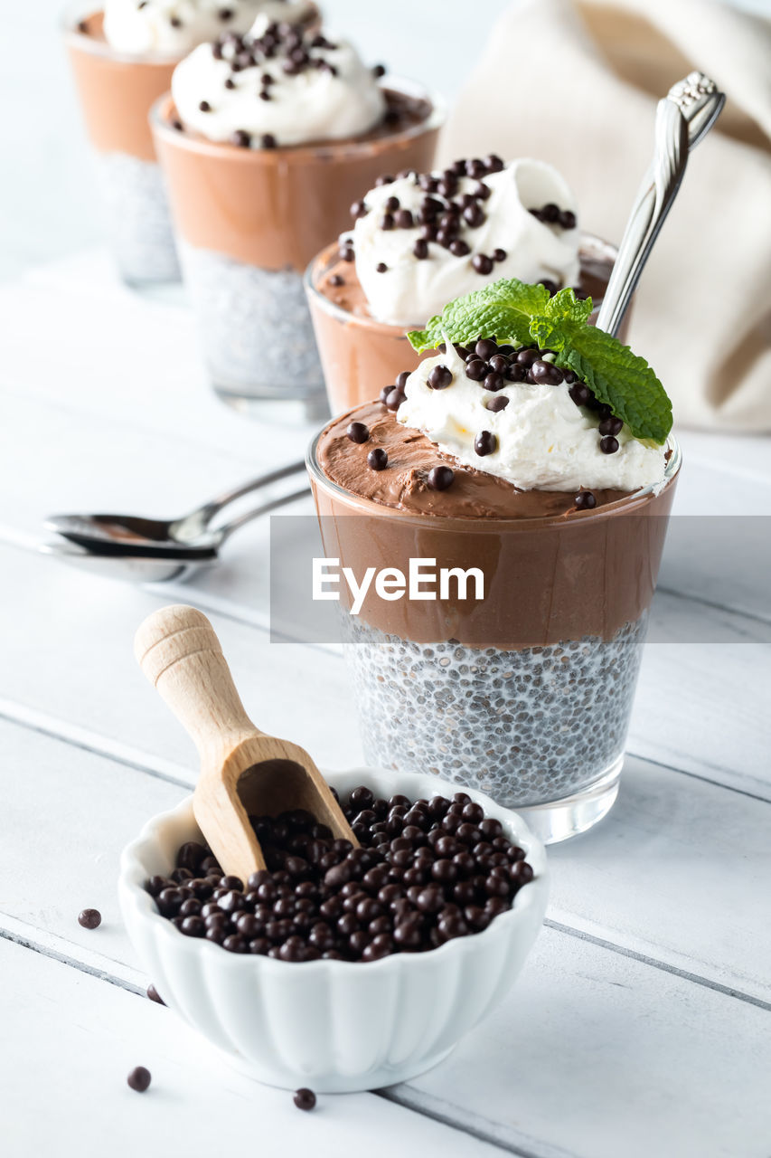 Chocolate chia pudding parfaits with a bowl of chocolate quinoa puffs in front.