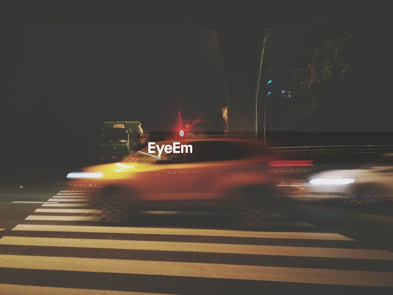 CLOSE-UP OF ILLUMINATED CARS ON STREET AT NIGHT