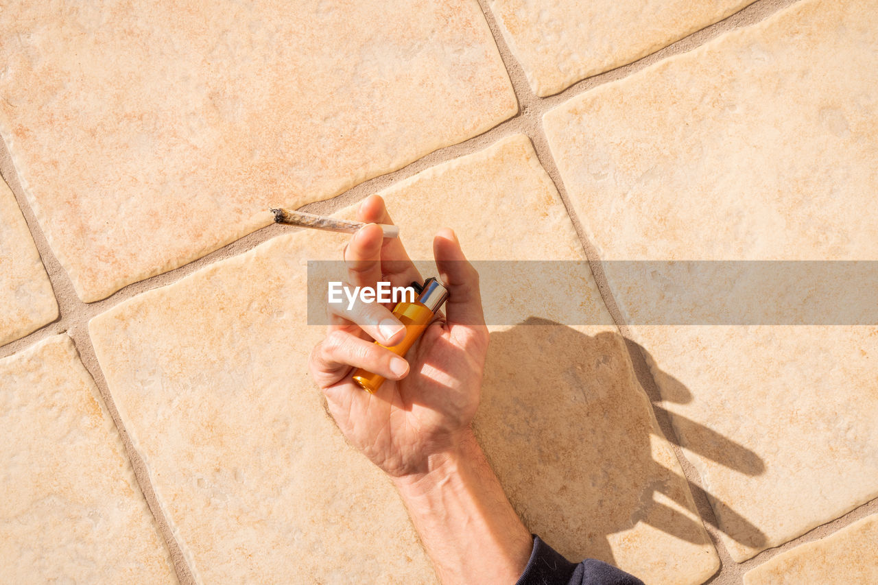 Hand of man holding cigarette and lighter