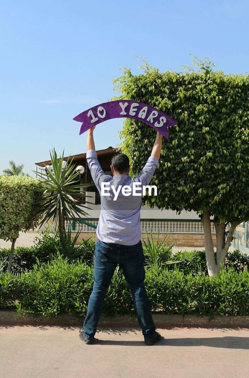 Full length of man holding 10 years anniversary banner