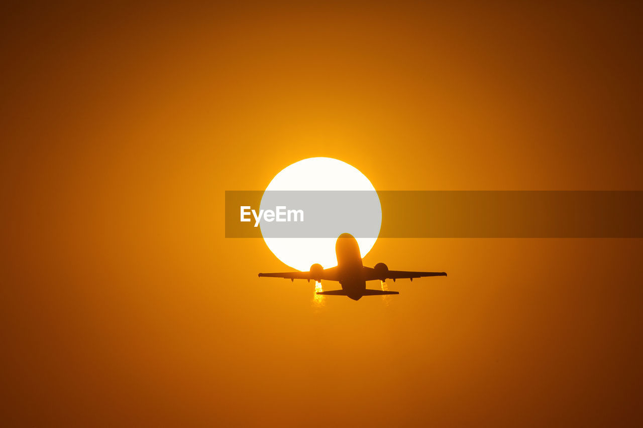 LOW ANGLE VIEW OF SILHOUETTE AIRPLANE AGAINST CLEAR SKY DURING SUNSET