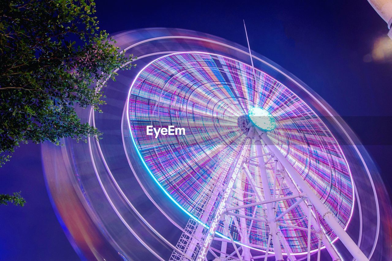 Illuminated ferris wheel against sky at night