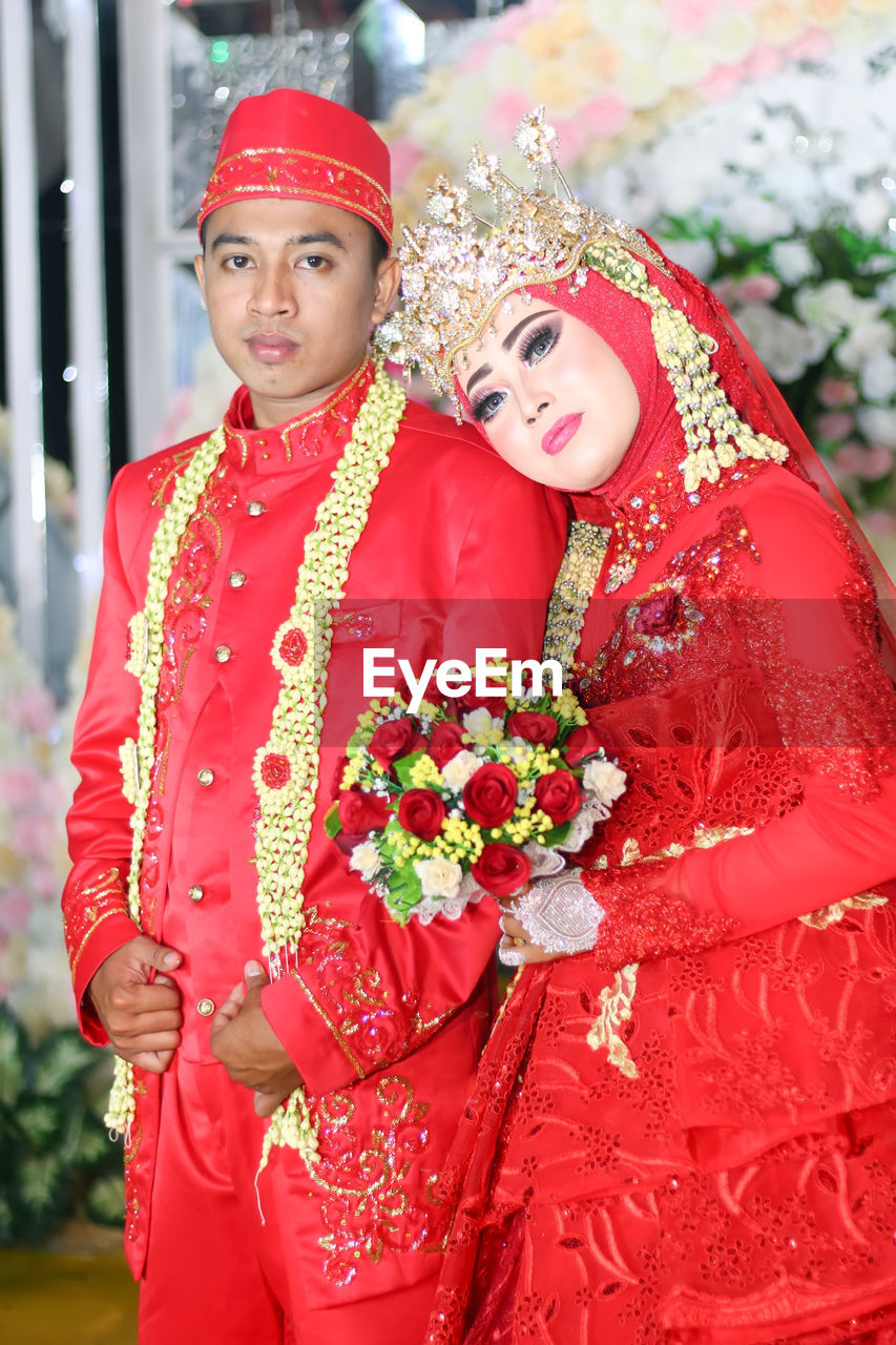 Portrait of newlywed couple wearing red clothing at wedding ceremony