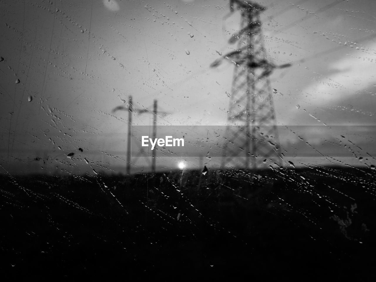 Close-up of wet glass window against sky during rainy season