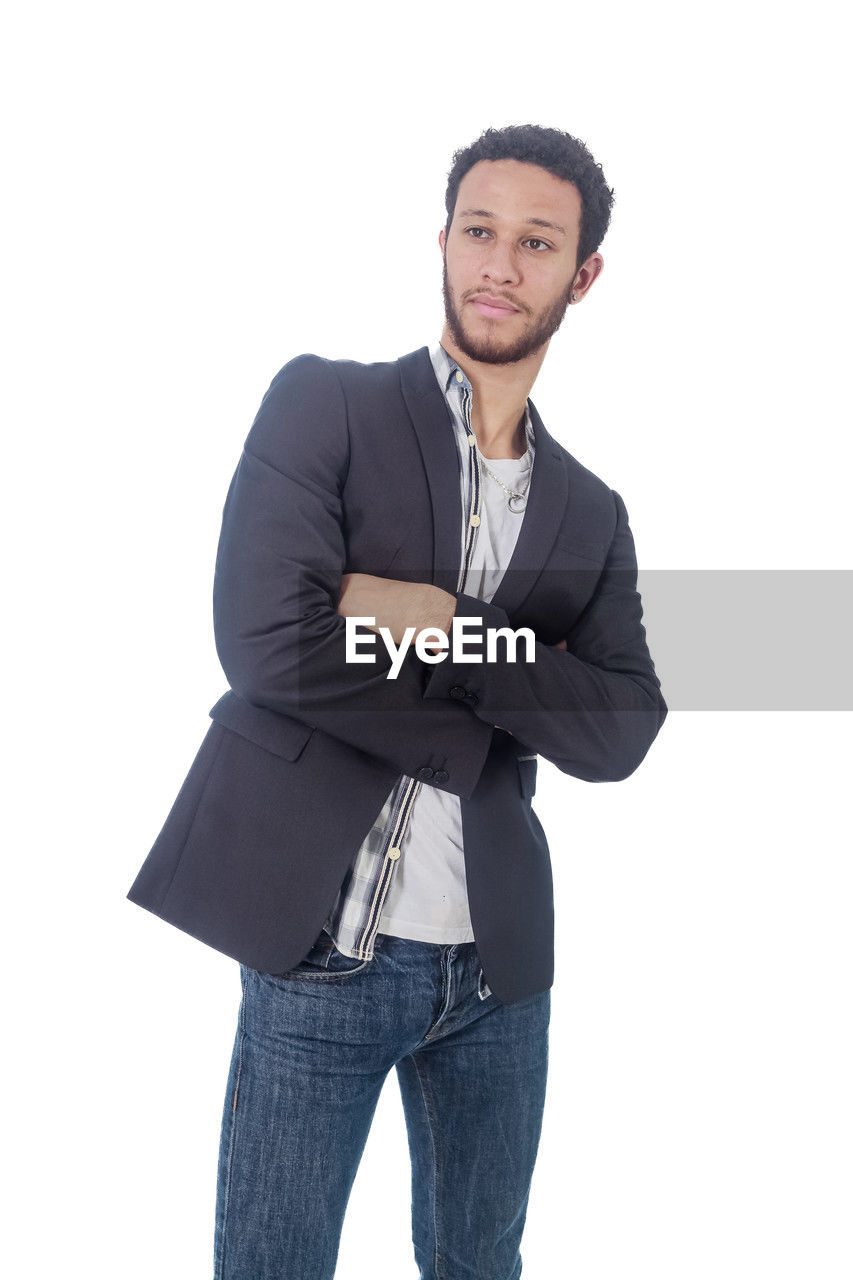 one person, white background, adult, portrait, clothing, outerwear, men, studio shot, cut out, looking at camera, sleeve, young adult, standing, business, jeans, smiling, indoors, jacket, emotion, casual clothing, collar, denim, formal wear, happiness, pocket, businessman, front view, fashion, three quarter length, shirt, hands in pockets, person, copy space, facial hair, beard, looking, trousers, business finance and industry, cool attitude