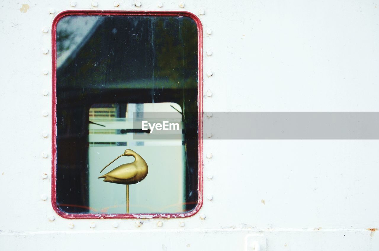 Golden bird figurine seen through boat window