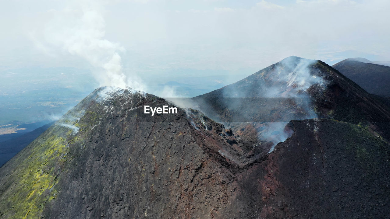 Crater etna top view from above in a panoramic aerial photo with sulphure and smoke at degassation