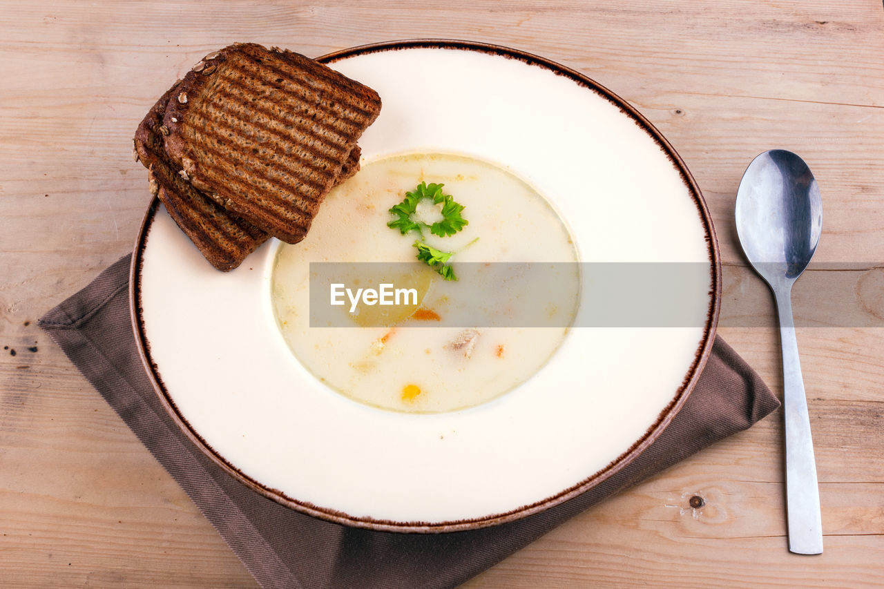 Cheese soup in clay plate with toasted bread