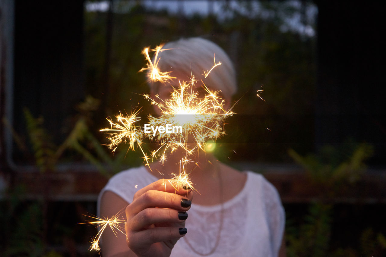 Close-up of woman holding illuminated sparkler