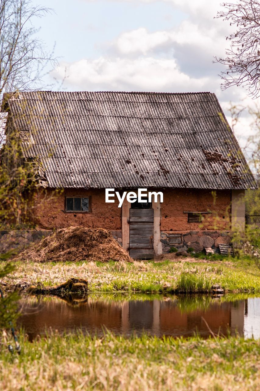 Old house made it clay near water against sky