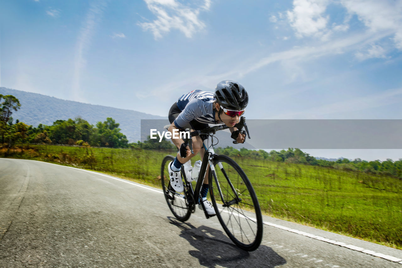 Man riding bicycle on road against sky