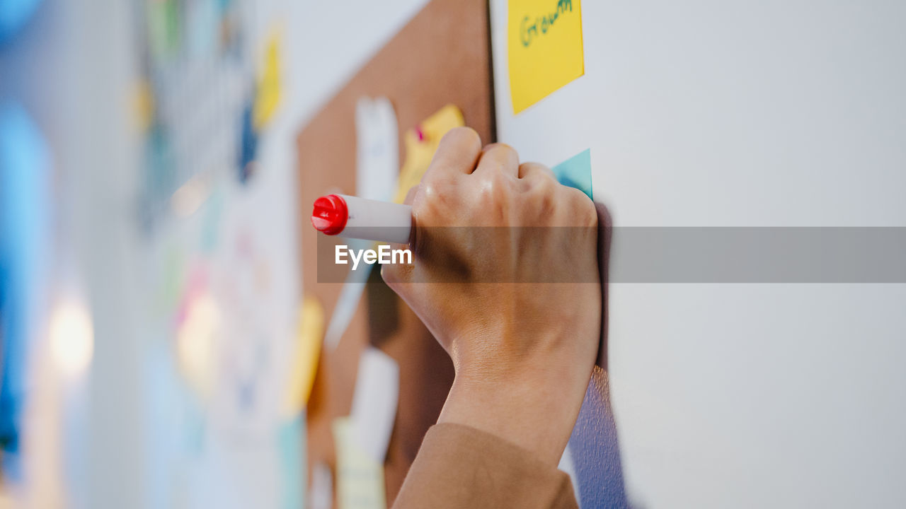 Cropped hand of woman writing on whiteboard 