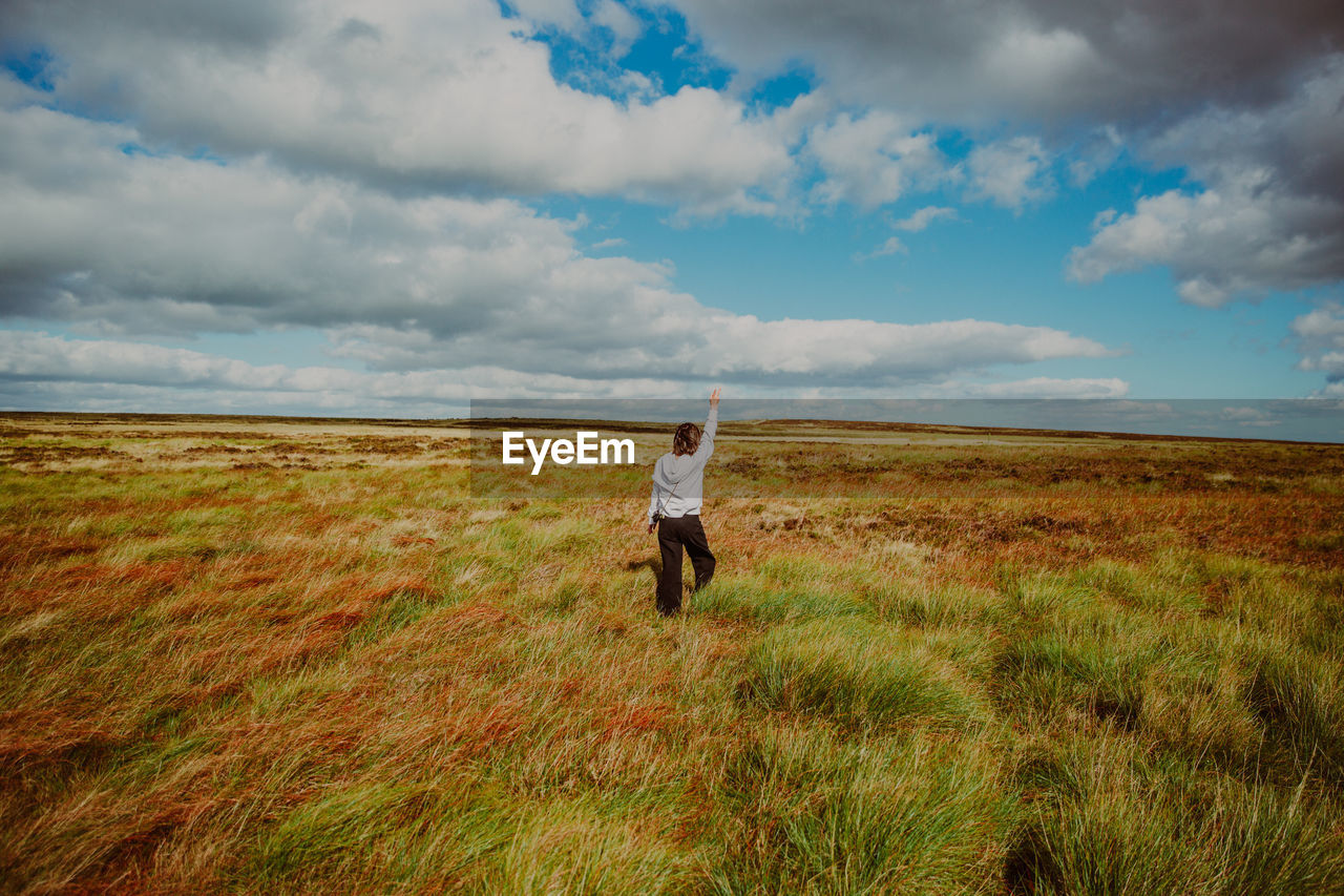 Rear view of man standing on field against sky