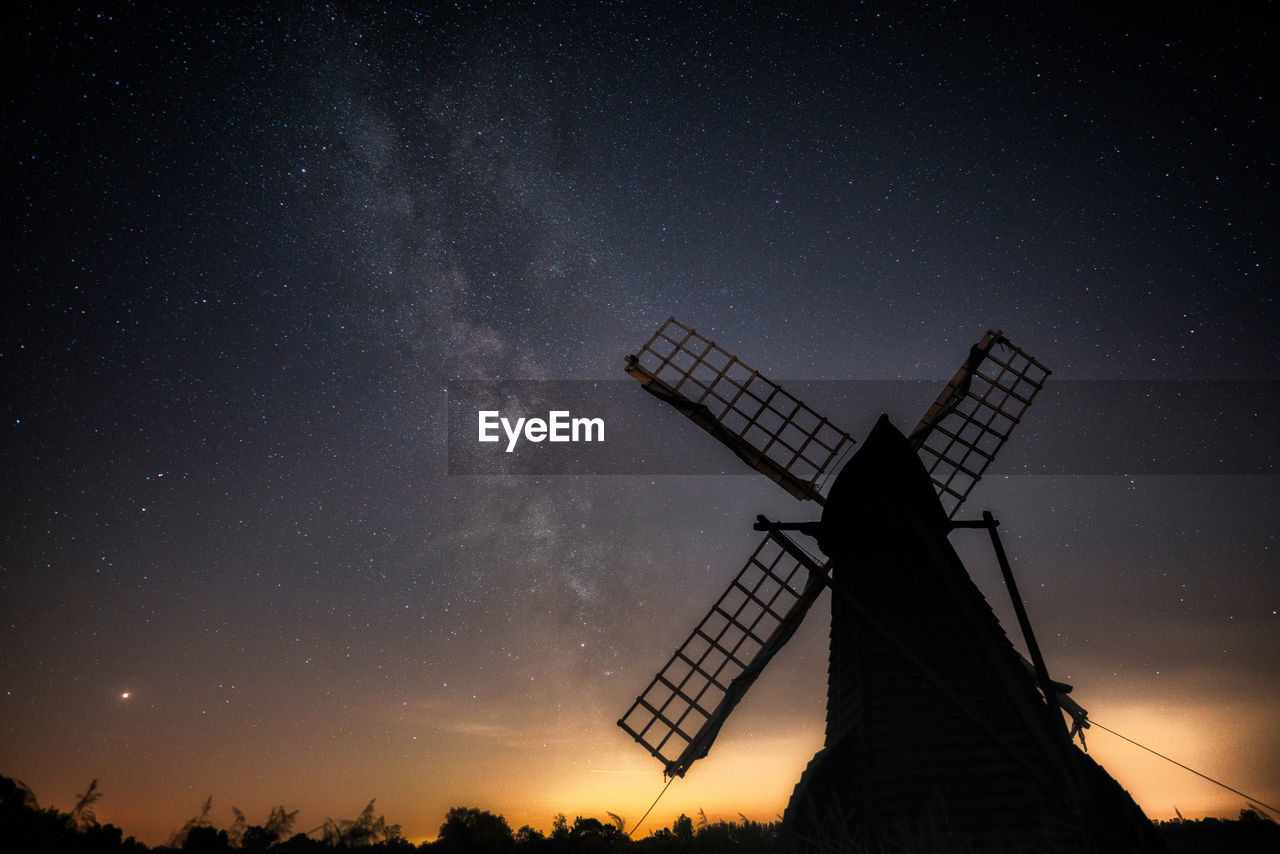 Low angle view of silhouette traditional windmill against sky at night