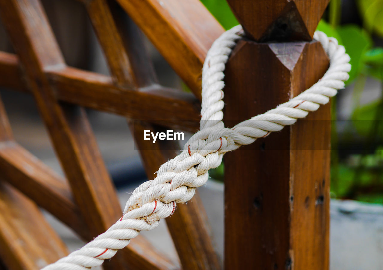 CLOSE-UP OF ROPES TIED ON WOODEN POST