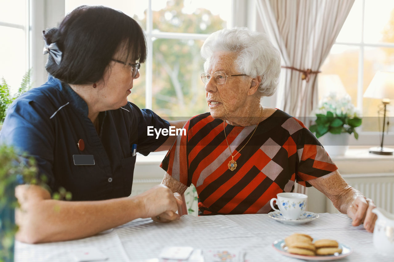 Female caretaker consoling senior woman at nursing home