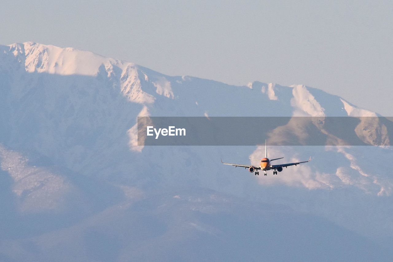 Low angle view of airplane flying against snowcapped mountains