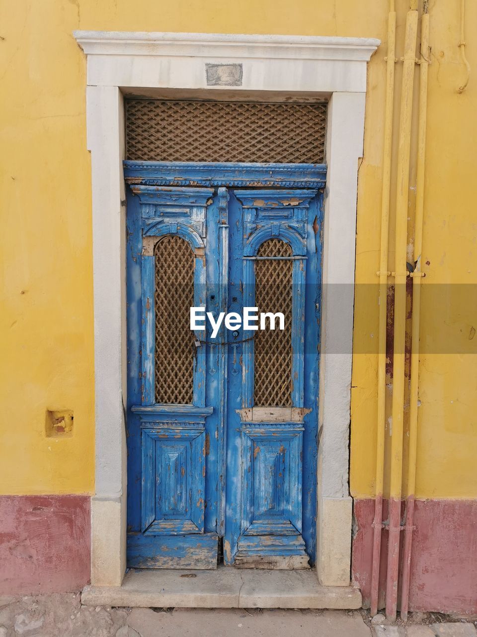 architecture, door, entrance, blue, building exterior, built structure, closed, building, wall, yellow, no people, security, protection, facade, window, house, day, residential district, old, wall - building feature, wood, outdoors, history, city, doorway, front door, iron, the past