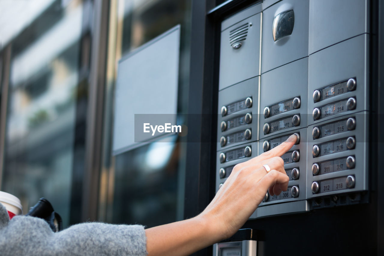 Cropped hand pressing button in building