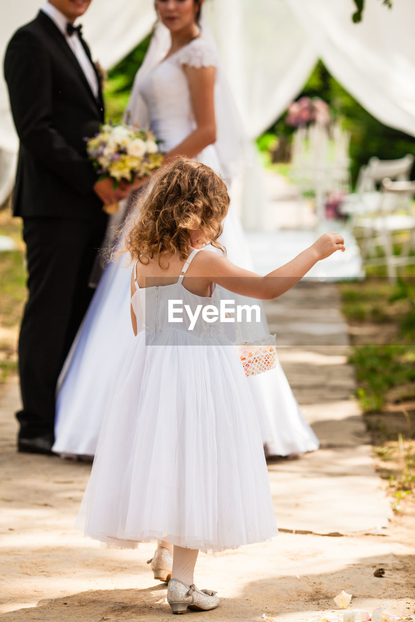 full length of bride and bridegroom holding hands while standing on road