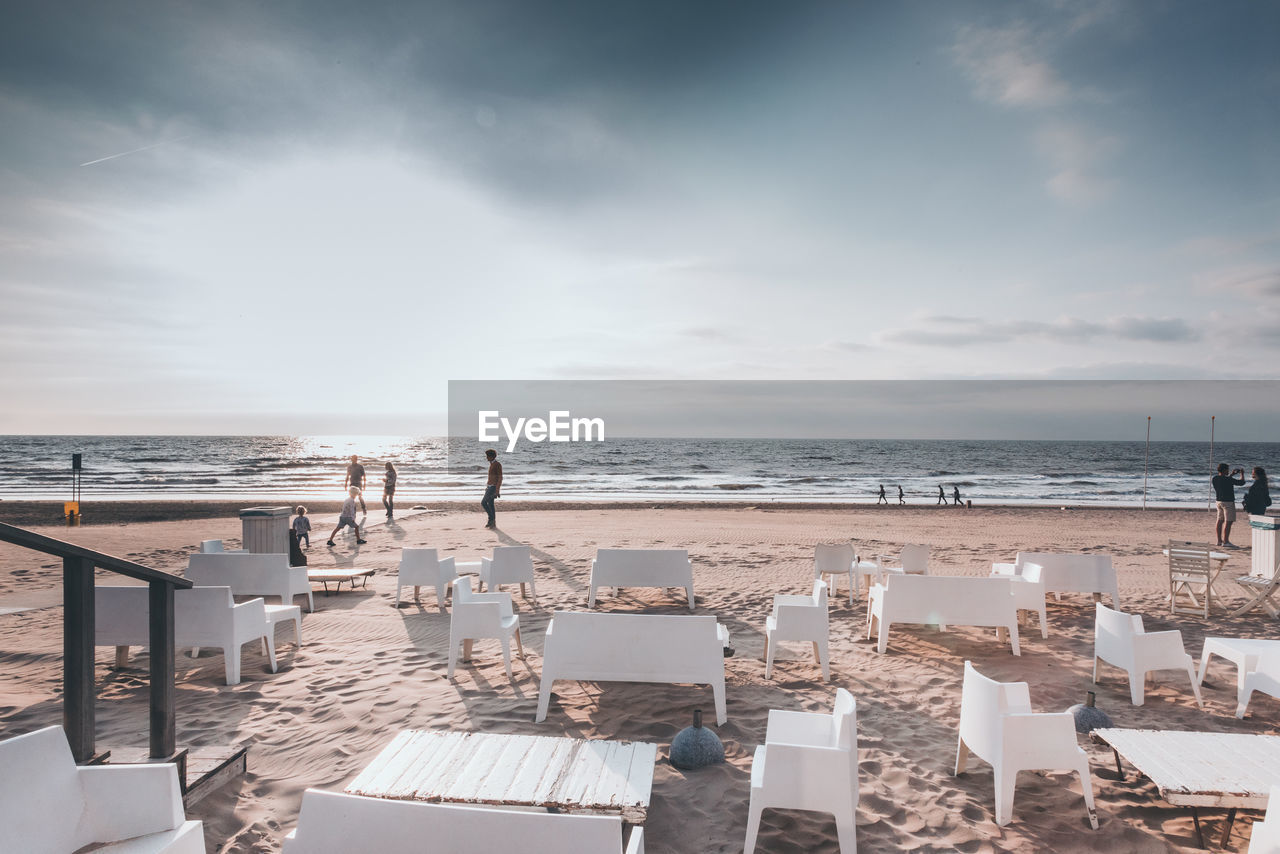 CHAIRS AND TABLE AT BEACH AGAINST SKY