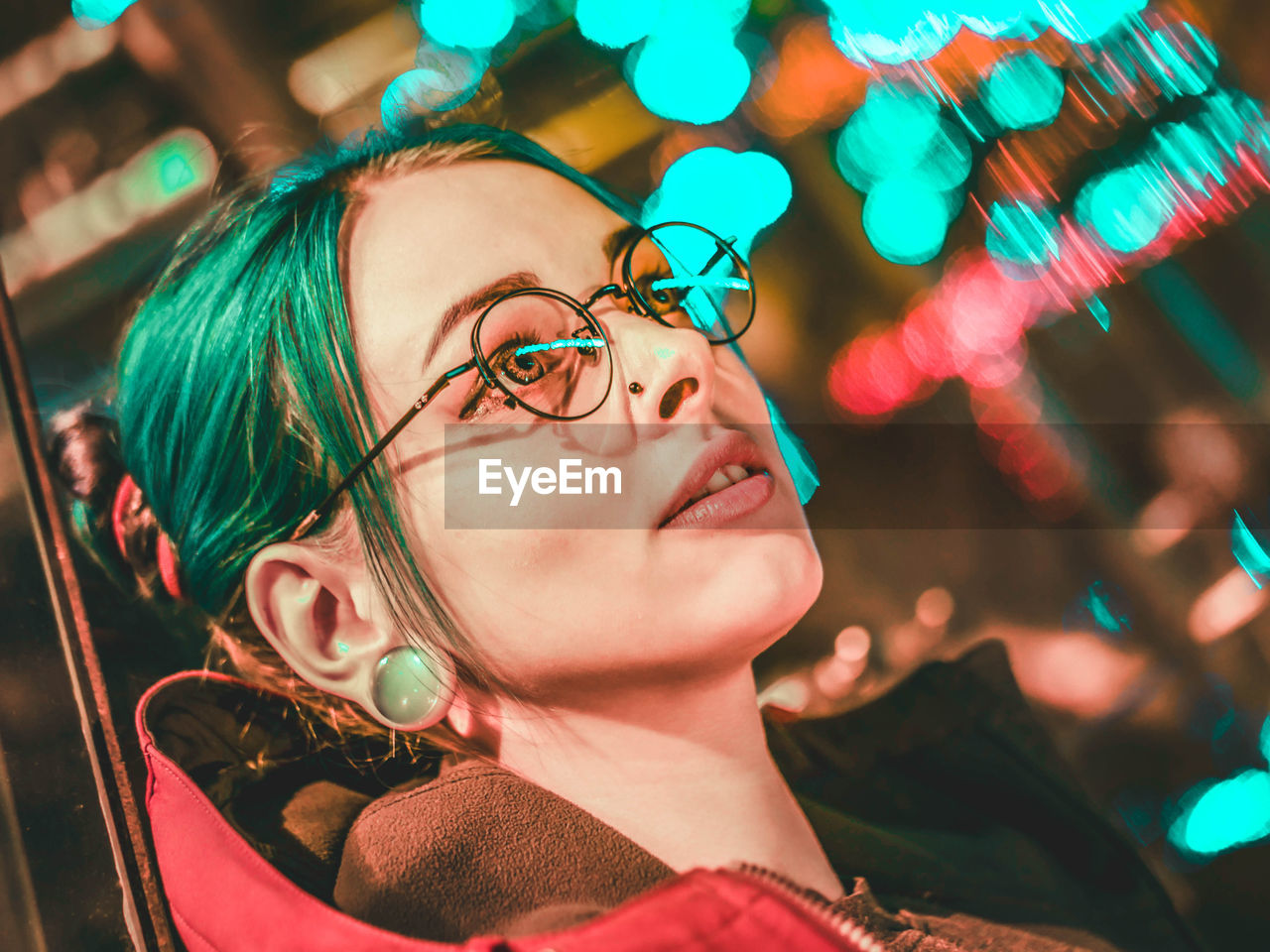 Close-up of young woman looking away while standing outdoors at night