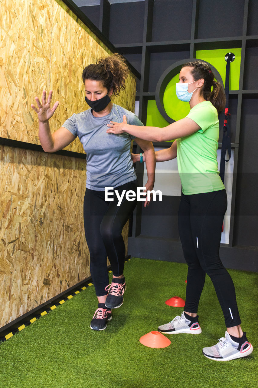 Full length of women wearing mask exercising at gym