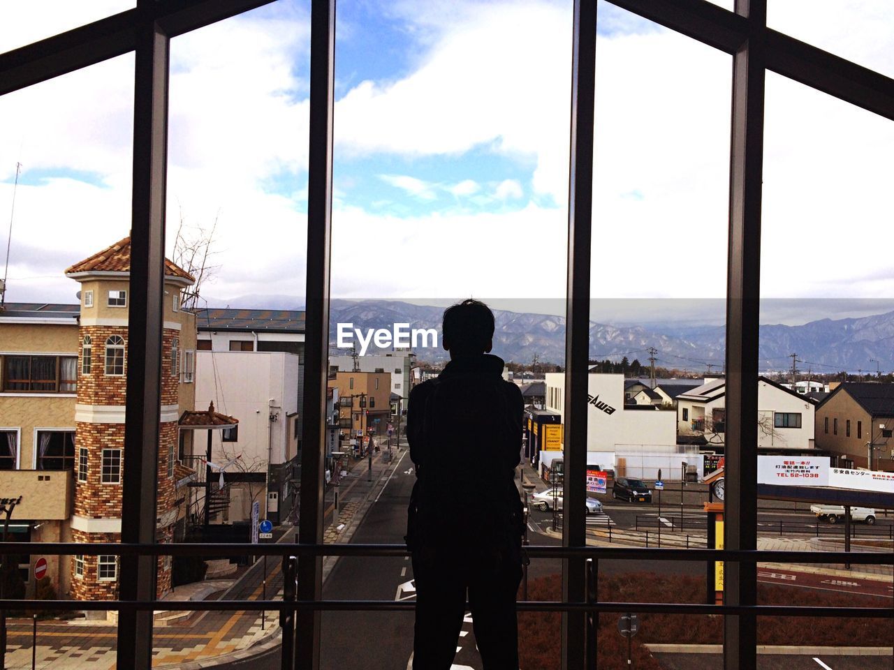 Rear view of man standing by window