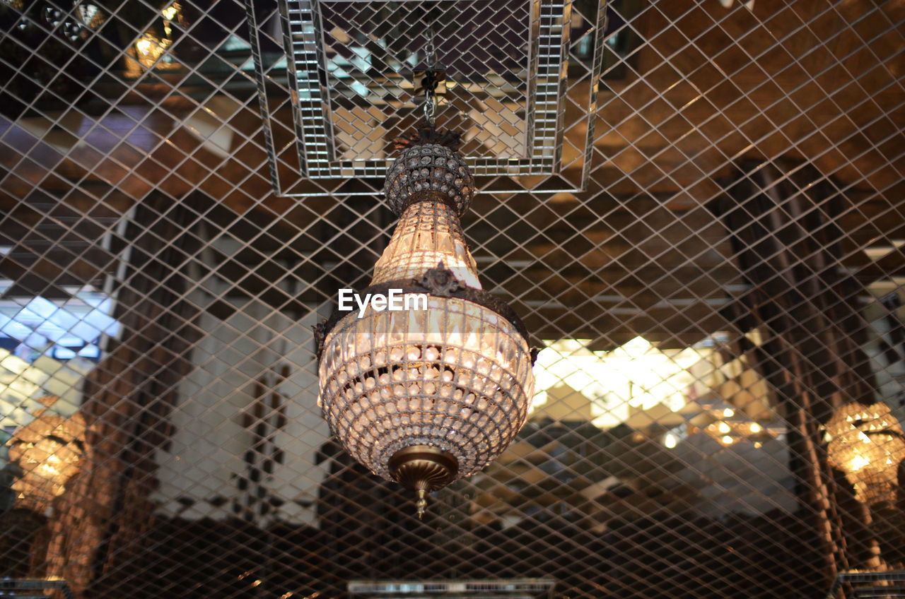 Low angle view of chandelier hanging from glass ceiling