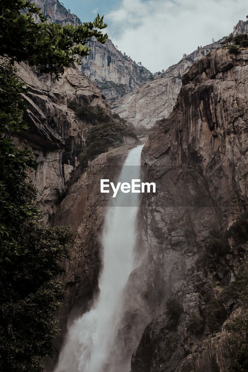 SCENIC VIEW OF WATERFALL AMIDST ROCKS