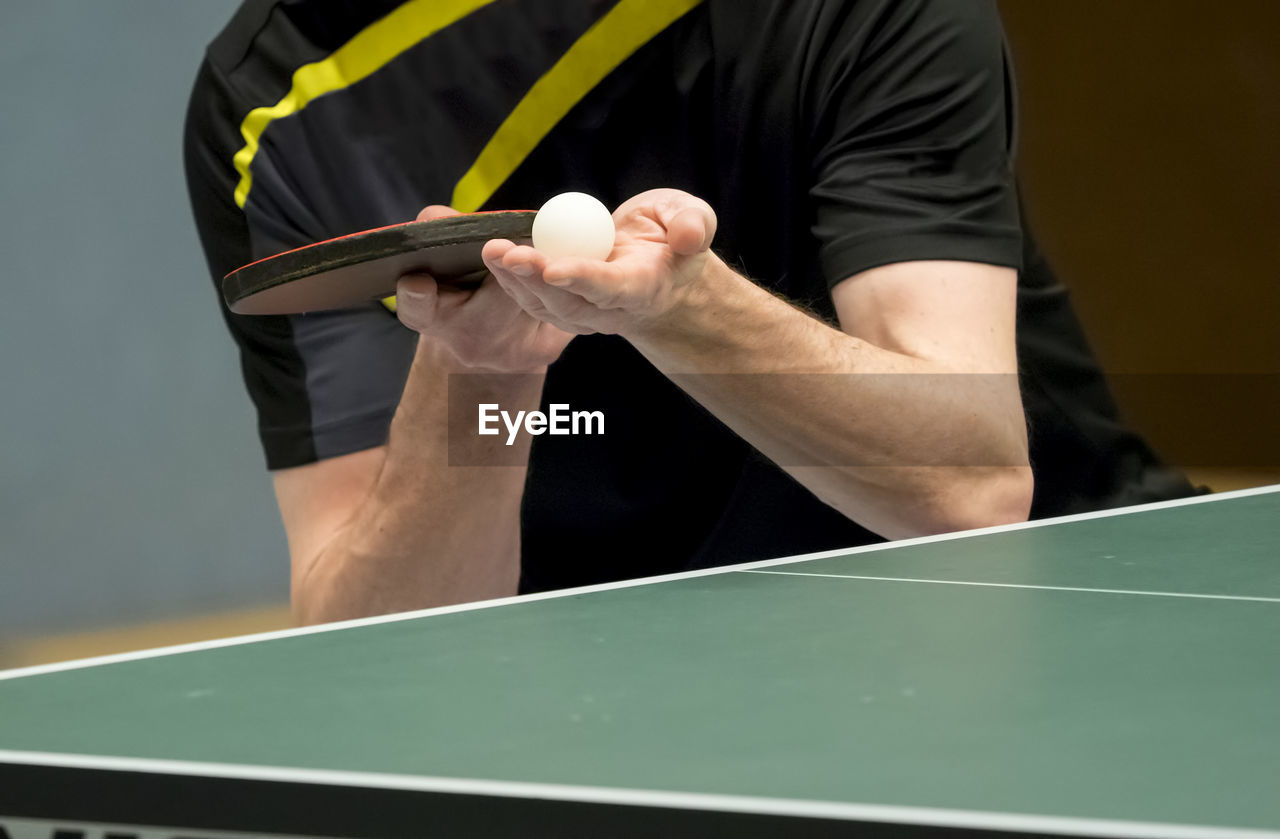 Midsection of man serving while playing table tennis