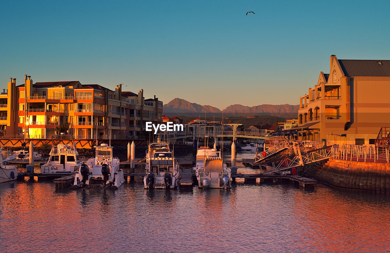 BUILDINGS BY RIVER AGAINST CLEAR SKY