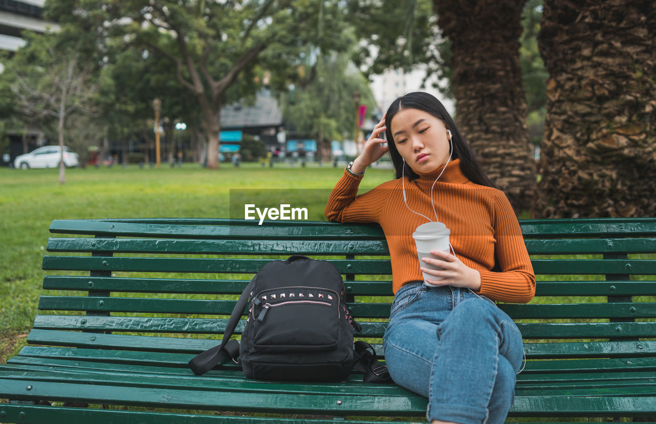 WOMAN SITTING ON BENCH IN PARK
