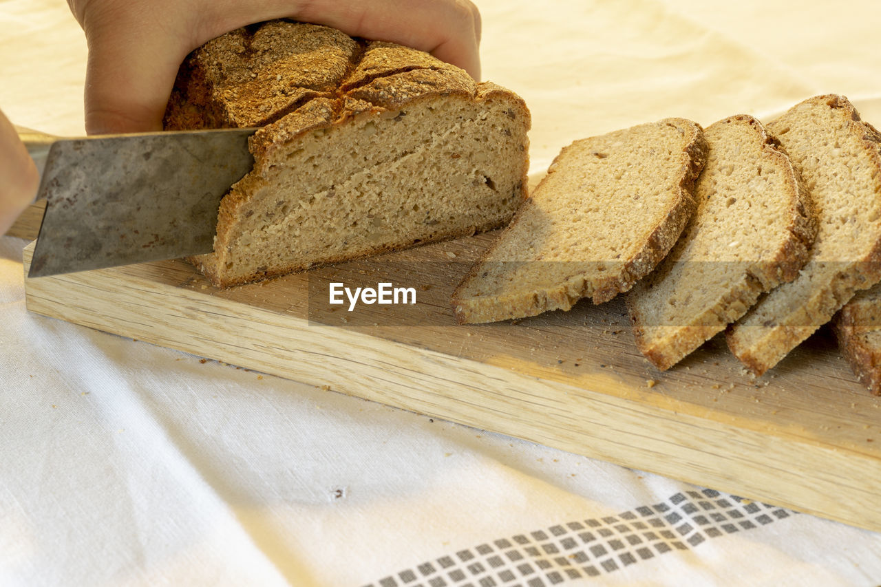 CLOSE-UP OF HAND HOLDING BREAD AND CUTTING BOARD