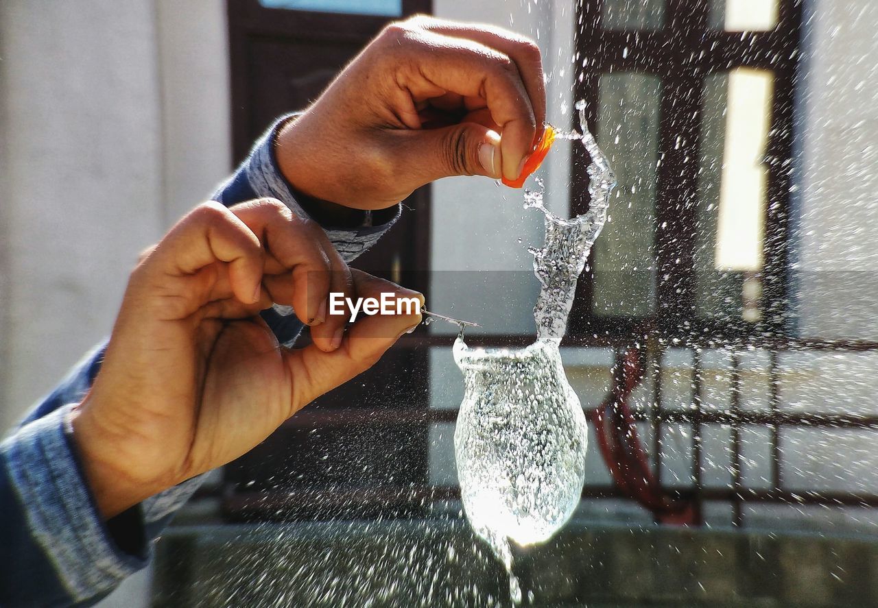 CLOSE-UP OF HAND HOLDING WET GLASS