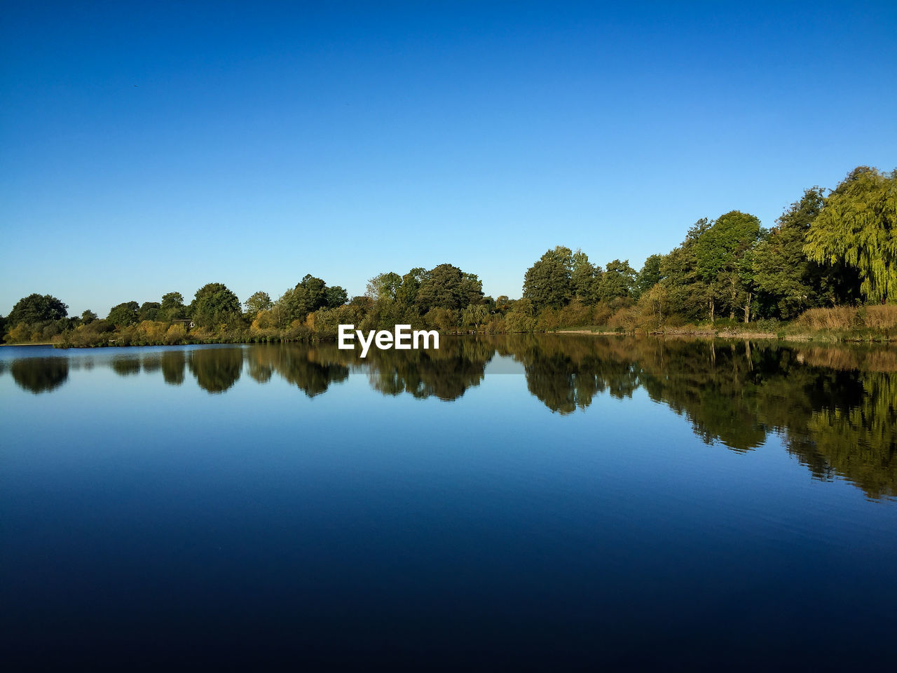 Scenic view of calm lake against blue sky